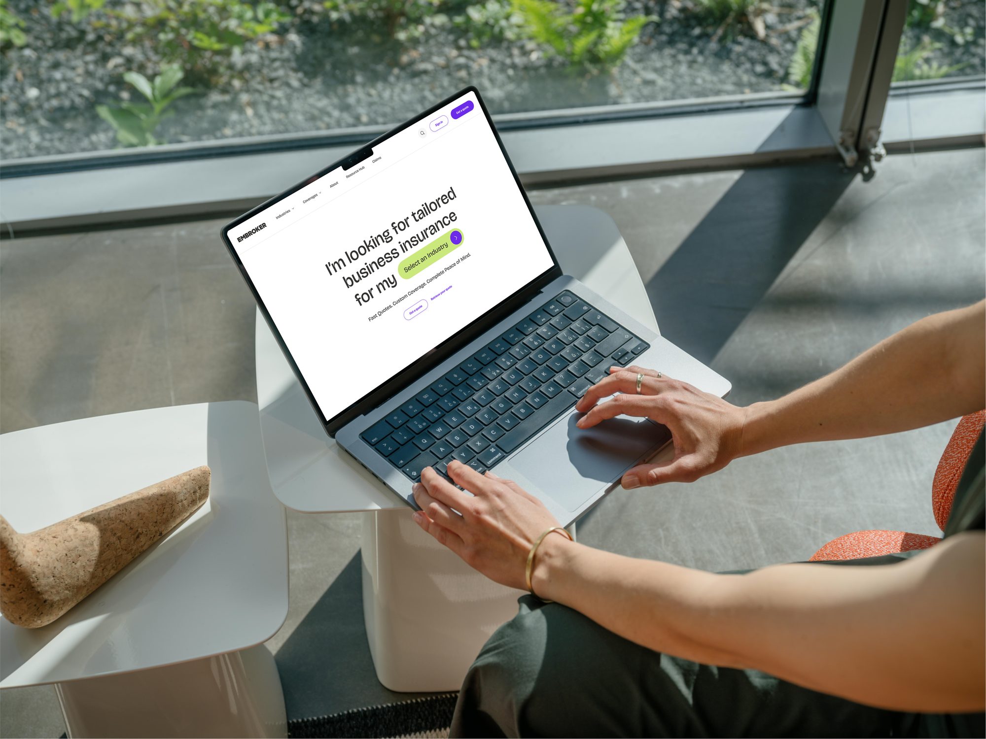Manos sobre una laptop con la nueva página de inicio de Embroker: I'm looking for tailored business insurance for my, select an industry