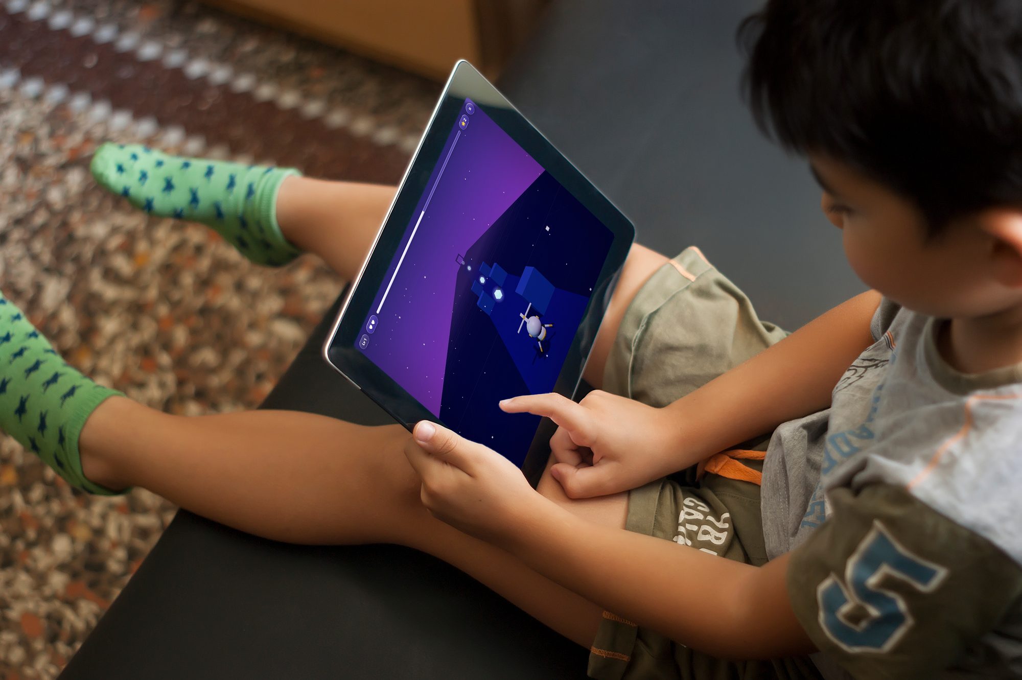 Un niño jugando Learn 2 Fly en una tableta, volando por el mundo morado del Espacio