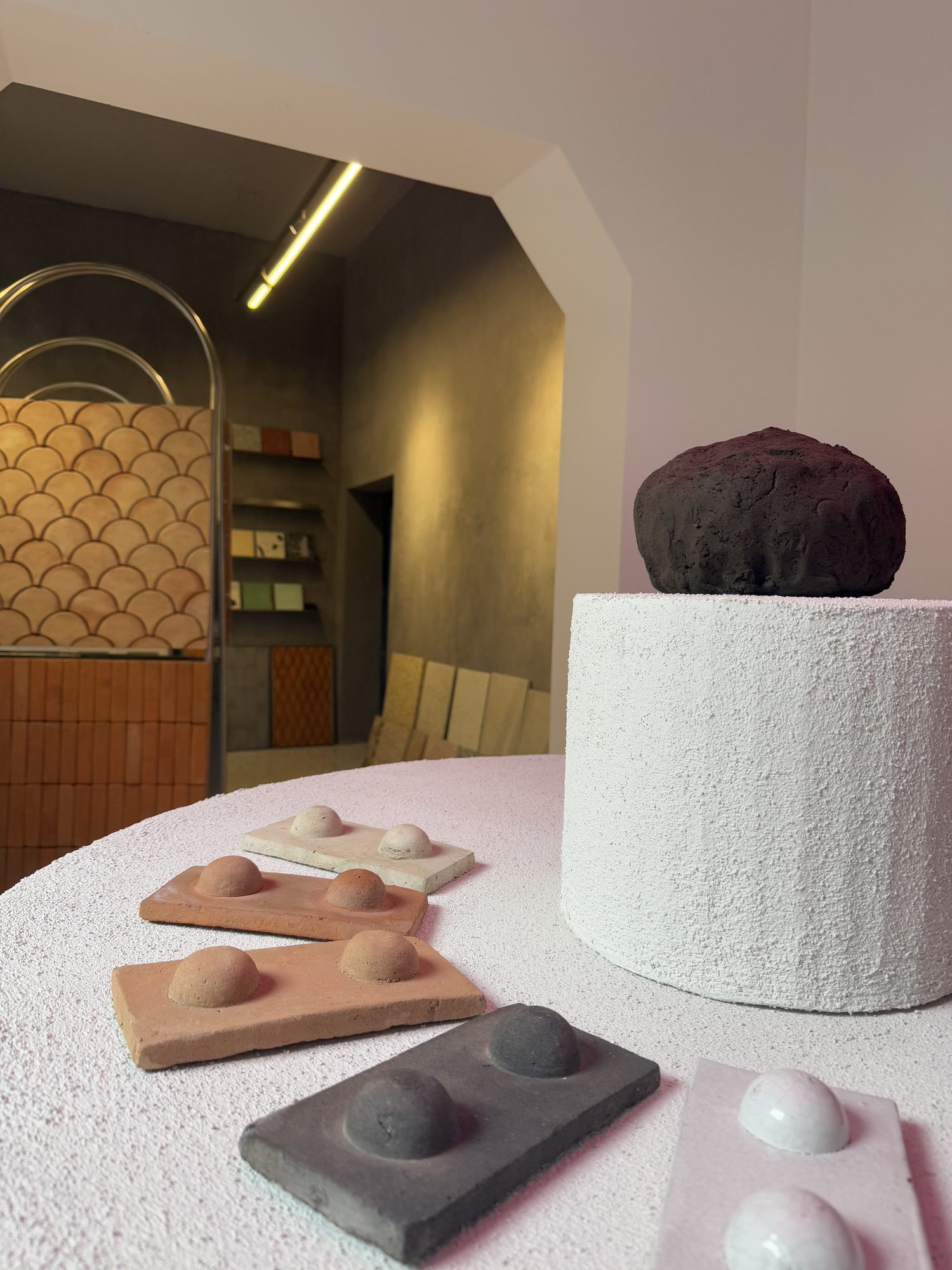 Azulejos de Luum y una piedra oscura sobre un pedestal blanco en el showroom